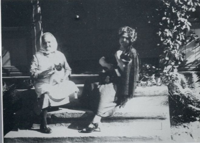 Uz mājas lieveņa Aspazija un mājkalpotāja Anniņa ar kaķiem. Foto no Rakstniecības, teātra un mūzikas muzeja krājuma