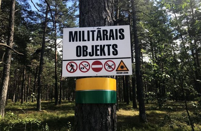 Uzraksts “Militārais objekts” un piktogrammas tā apakšā nozīmē, ka tālāk doties nav brīv, lai arī kā sviesta bekas, mellenes, patronu čaulītes un citas meža veltes aicinātu.